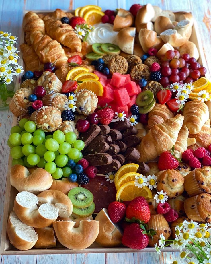 a platter filled with lots of different types of breads and pastries on top of a wooden table