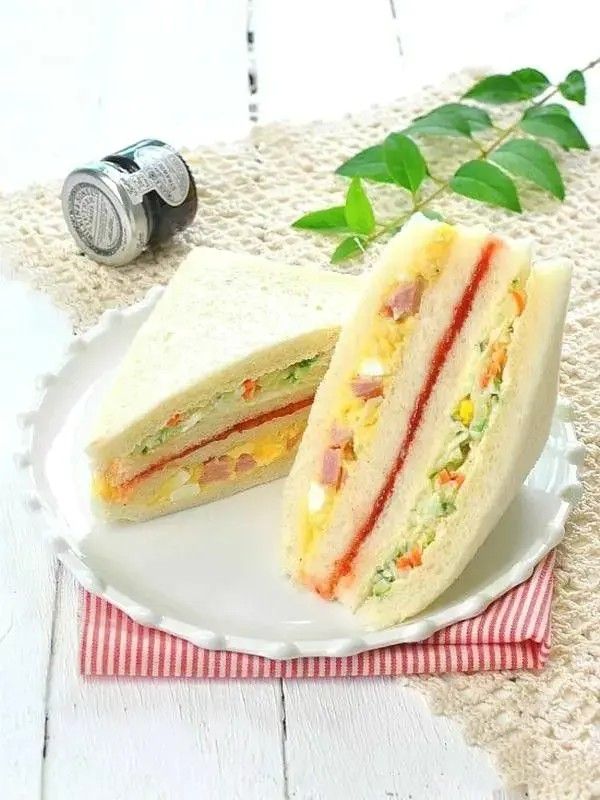 a cut in half sandwich sitting on top of a white plate next to a green leaf