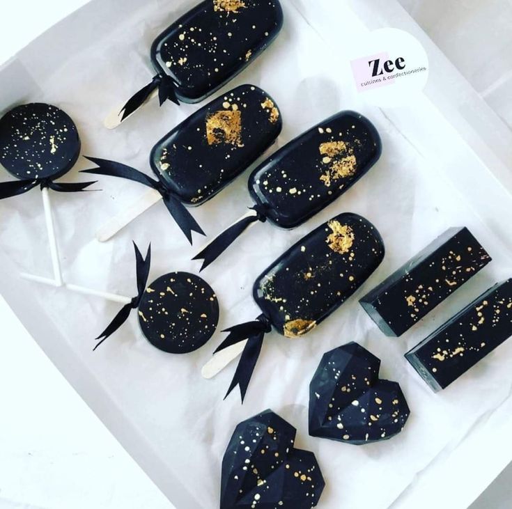 black and gold desserts are on display in a box