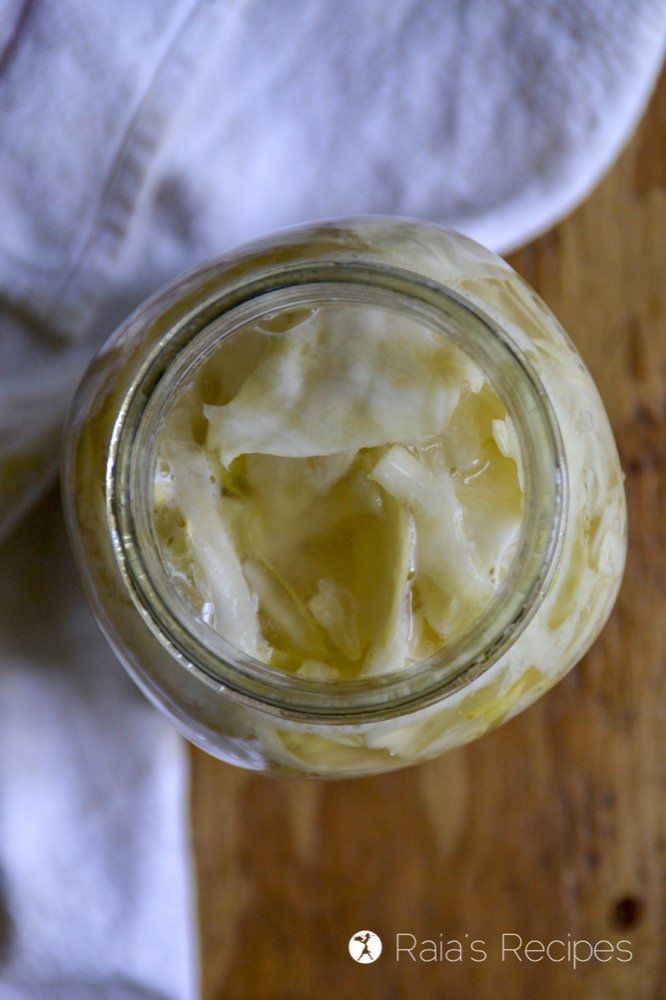 a glass jar filled with food sitting on top of a wooden table next to a white towel