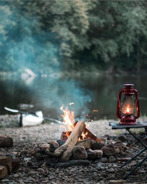 a red lantern sitting on top of a fire next to a pile of rocks and logs