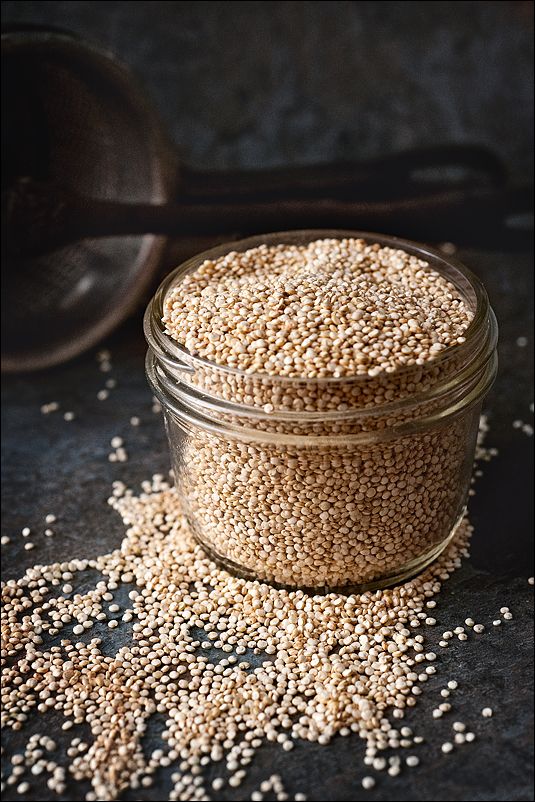 a glass jar filled with sesame seeds on top of a black surface next to a spoon