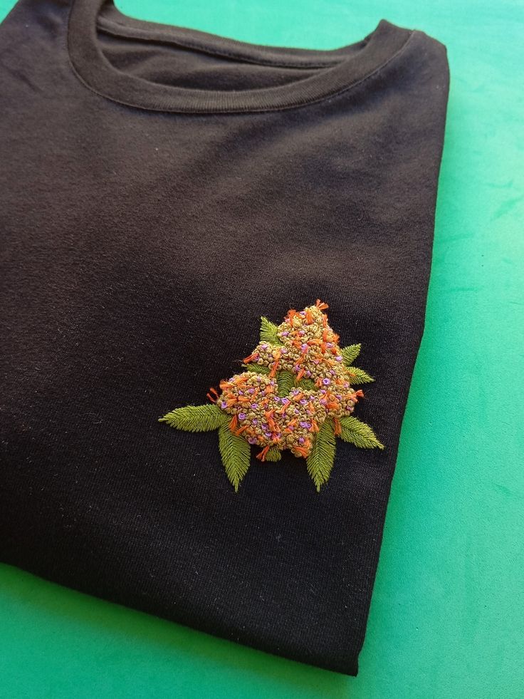 a black t - shirt with an embroidered flower on it