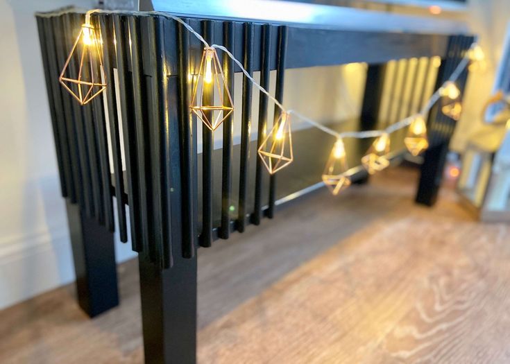 some lights that are on top of a black table in front of a mirror and wooden floor