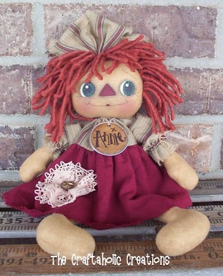 a little doll with red hair sitting on a shelf next to a brick wall and holding a donut