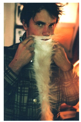 a man is brushing his beard with long white fur on top of it's head