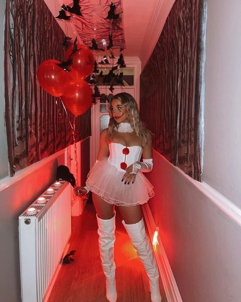 a woman in a costume is walking down the hallway with balloons and bats hanging from the ceiling