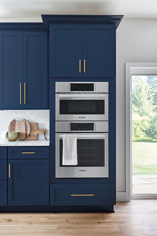 a kitchen with blue cabinets and white counter tops, two ovens are built into the wall