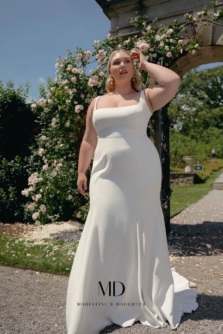 a woman in a white dress posing for the camera with her hand on her head