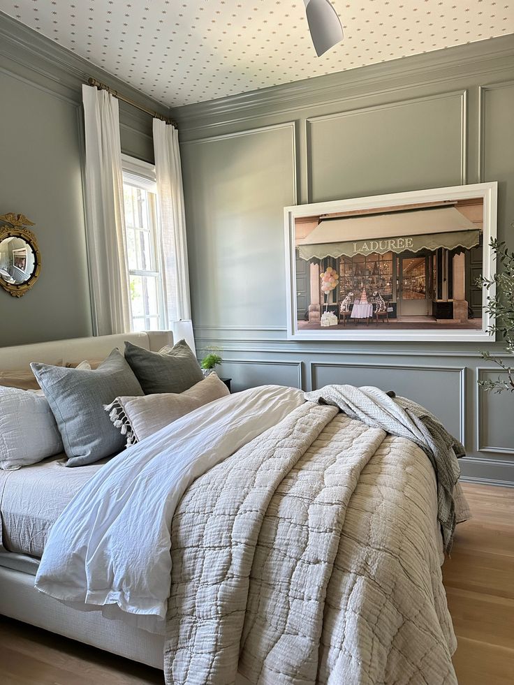 a bed with white sheets and pillows in a bedroom next to a painting on the wall