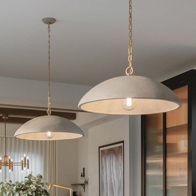 two pendant lights hanging from the ceiling in a living room next to a potted plant