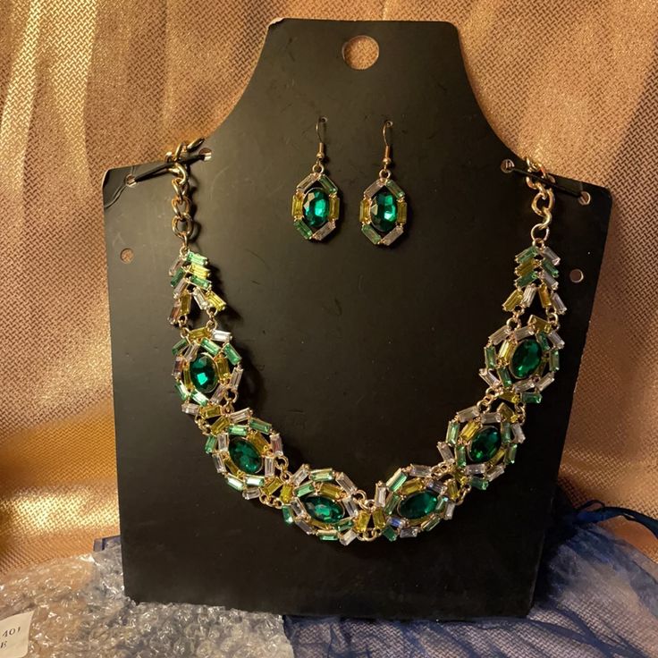 Beautiful Necklace Set With Matching Earrings. Large Green Jewel In The Middle With Yellow And Clear Jewels Around The Large Green Stone With Gold Colored Chain. Necklace Has Extender Chain And Earrings Are On Fish Hooks. Brand New In Package. Comes With Blue Tie Bag. Nice Set For A Christmas Gift. Green Metal Jewelry For Formal Occasions, Formal Green Metal Jewelry, Green Metal Necklaces With Matching Earrings, Green Metal Jewelry For Party, Green Metal Jewelry For Parties, Green Crystal Jewelry For Party, Green Crystal Jewelry With Jeweled Details, Formal Green Jeweled Jewelry Sets, Green Dangle Costume Jewelry