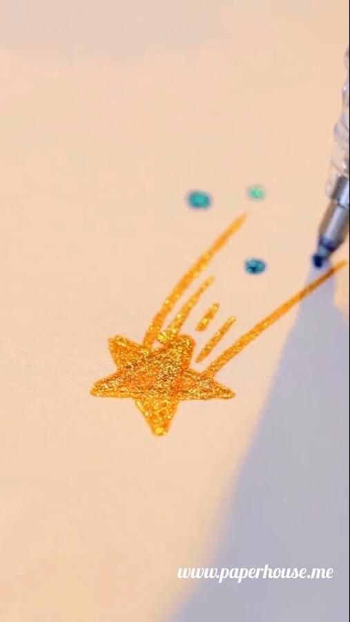 a pen is writing on paper with gold glitter