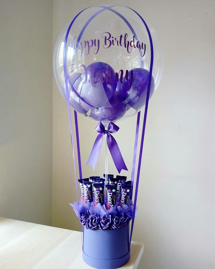 a birthday balloon with chocolates in it on a shelf next to a window sill