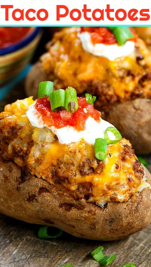 two loaded baked potatoes sitting on top of a wooden table next to a bowl of salsa