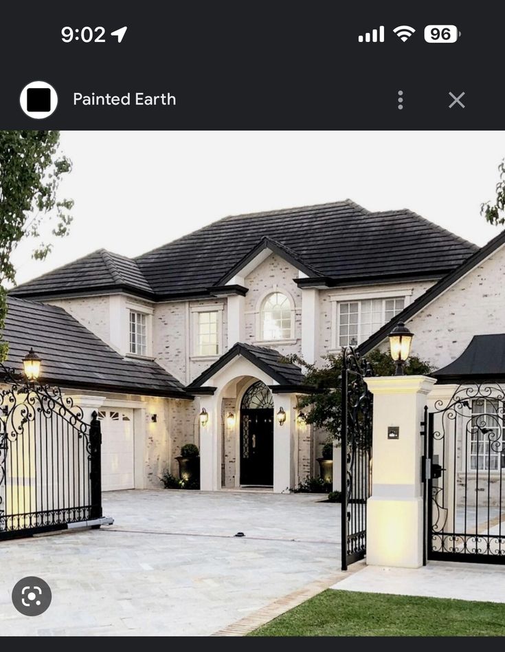 a large white house with a black gate and lights on it's front entrance