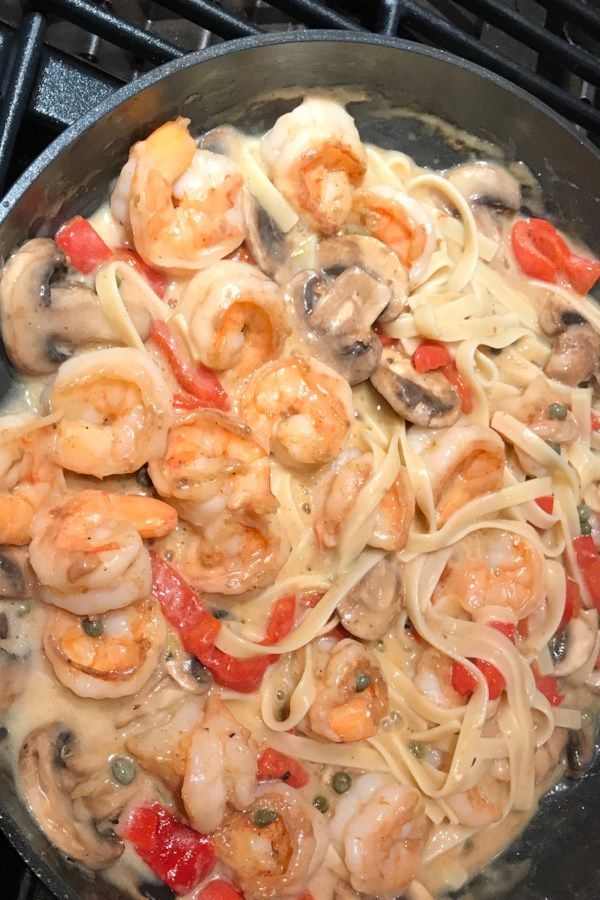 pasta with shrimp, mushrooms and peppers in a skillet on the stove burner