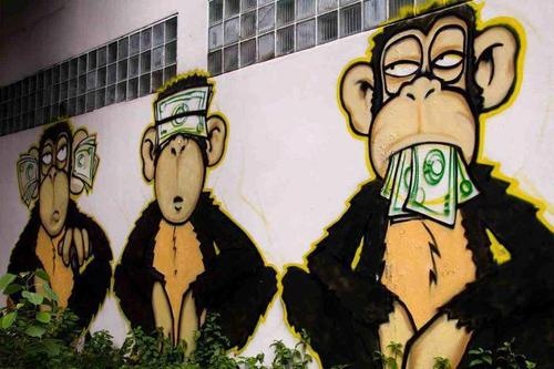 graffiti on the side of a building depicting three monkeys with money bills in their mouths