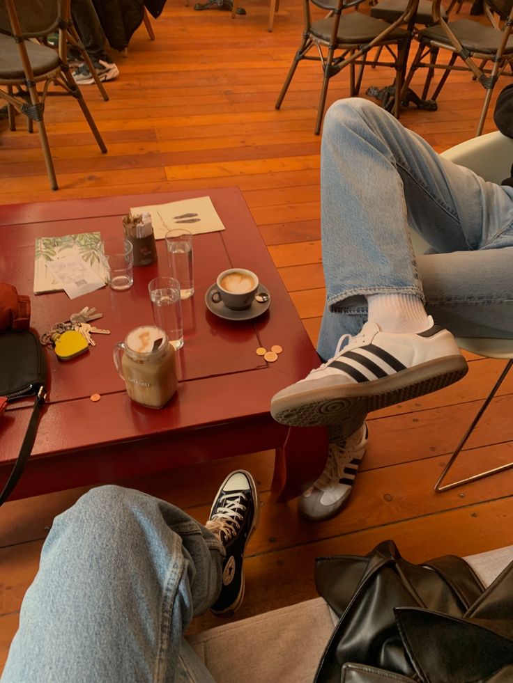 two people sitting at a table with their feet propped up on the coffee table in front of them