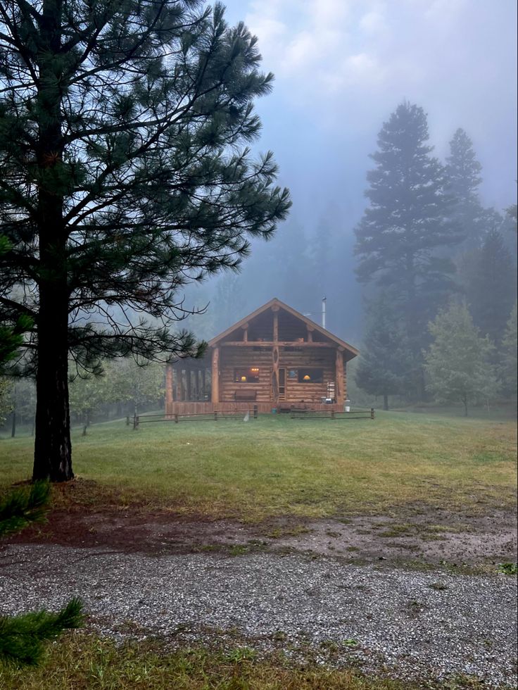 a log cabin in the woods on a foggy day