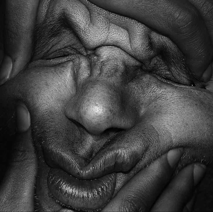 black and white photograph of two hands covering the face of a man