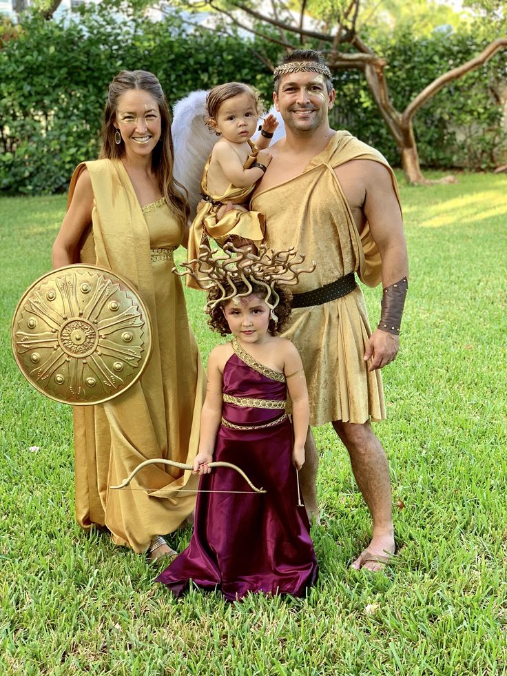 a family dressed up in ancient greek costumes posing for a photo with an infant on her lap