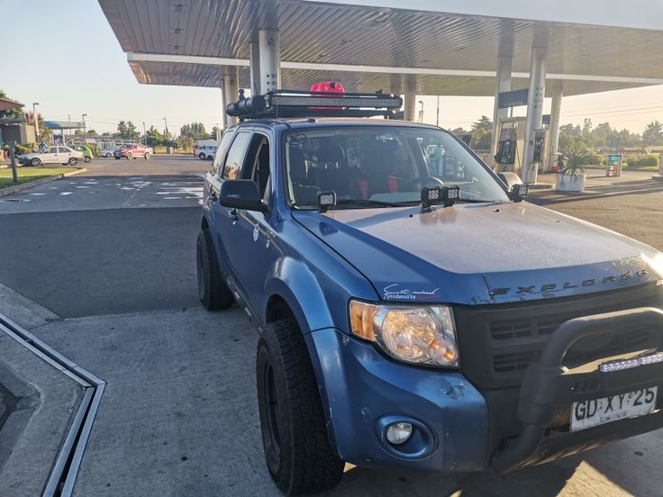 a blue pick up truck parked in front of a gas station with its lights on