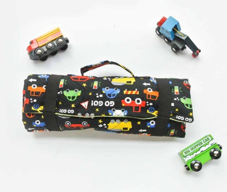 a black bag with cars and trucks on it next to some toy vehicles in front of it