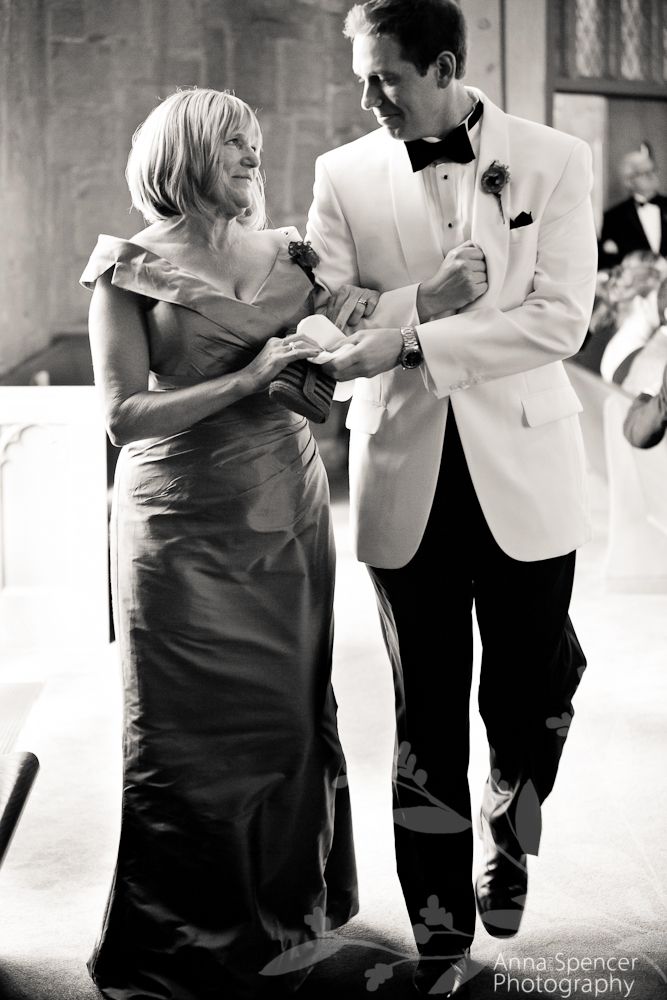 a man in a tuxedo helping a woman put on her dress