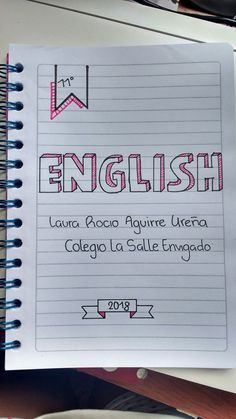 a notebook with the words english written in pink and red on it next to a cup of coffee