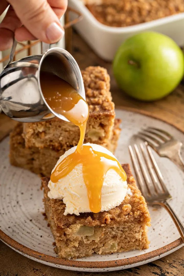 someone pouring caramel sauce on top of some dessert bars with apples in the background