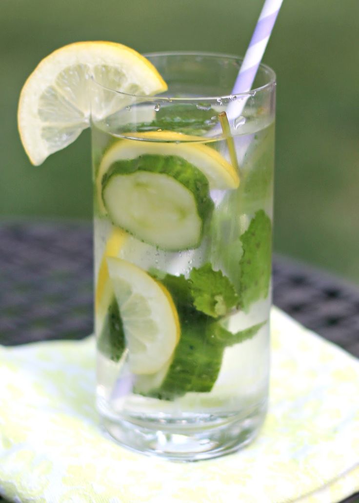 a glass filled with cucumber and lemonade sitting on top of a table