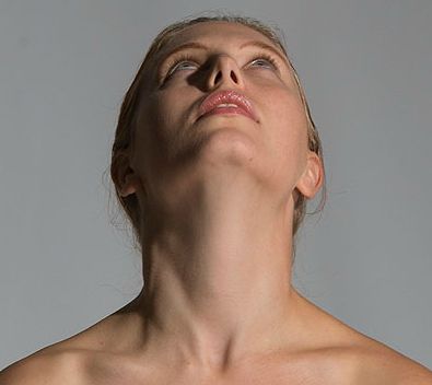 a woman with her eyes closed is looking up at something in the air above her head