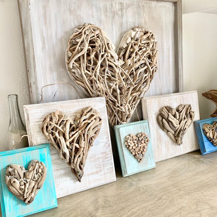 three framed hearts are displayed on a table next to two vases with flowers in them