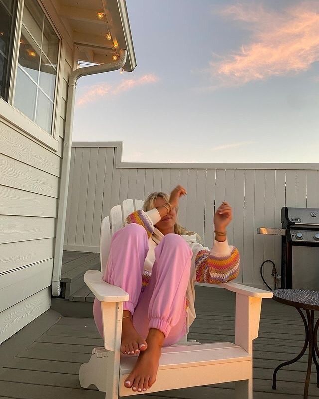 a woman sitting in a chair on top of a wooden deck next to a bbq