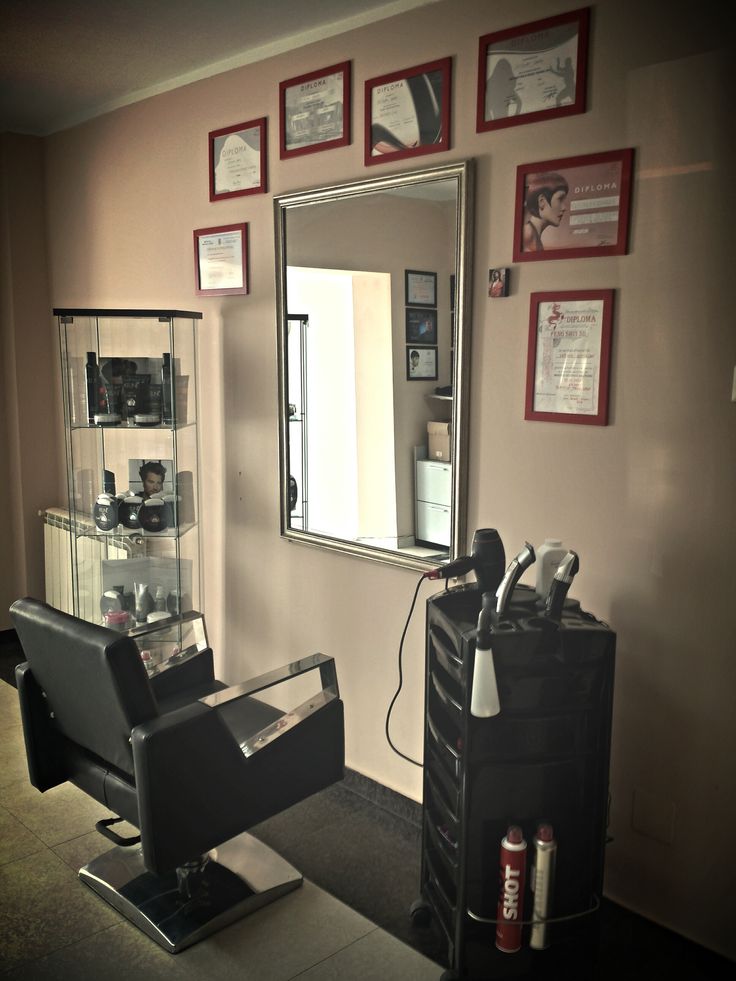 a hair salon with a mirror, chair and other items on the wall in front of it