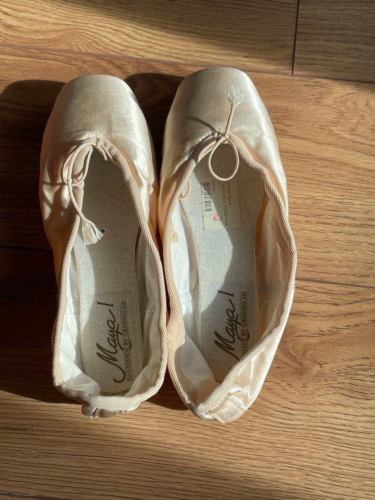 two pairs of ballet shoes sitting on top of a wooden floor