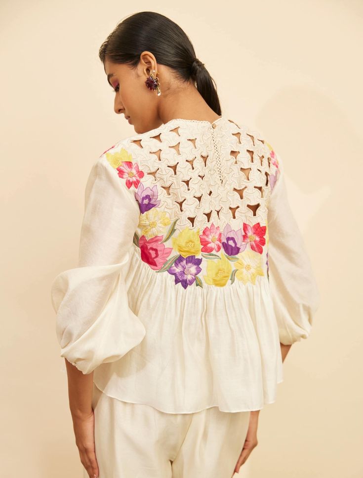 Editor's Note Featuring an ivory chanderi floral applique and cutwork top Note: Pant worn by model is for styling purposes and can be purchased separately. Color: Ivory Fabric: Chanderi Component: Top Occasion: Resort and daywear Care: Dry Clean Only About the Designer Chandrima celebrates diversity in cultures and craft forms creating ready-to-wear women wear for the urban woman of today. The brand embodies the idea of Indian handloom and craft merged with an international style. Label Chandrim White Top With Cutwork Hem For Spring, Feminine Chikankari Embroidery Tops For Spring, Feminine Chikankari Tops For Spring, Feminine Chikankari Embroidered Tops For Spring, Feminine Spring Tops With Chikankari Embroidery, White Cutwork Hem Blouse For Summer, White Blouse With Cutwork Hem For Spring, White Cutwork Hem Summer Blouse, White Summer Blouse With Cutwork Hem