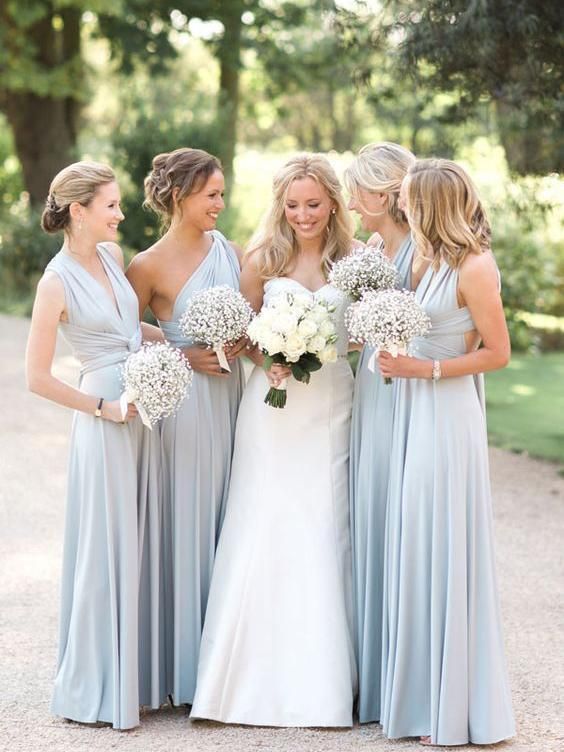 a group of women standing next to each other in front of trees and grass with bouquets