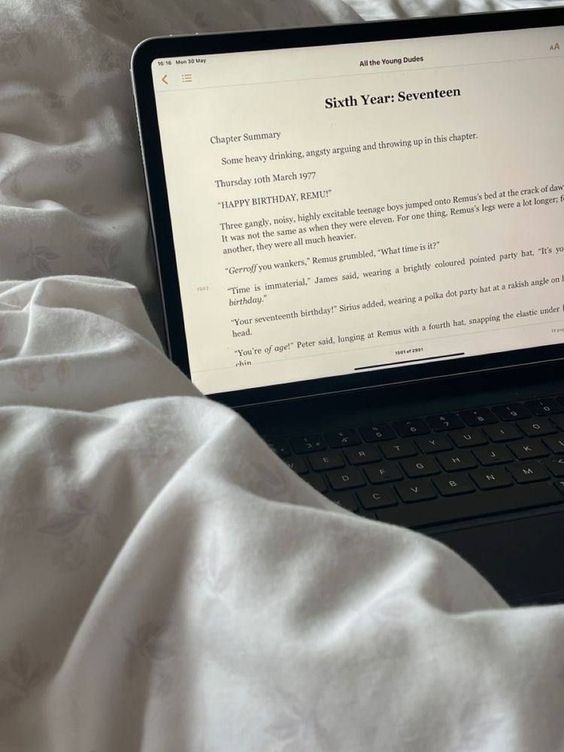 an open laptop computer sitting on top of a white sheet covered bedspread,