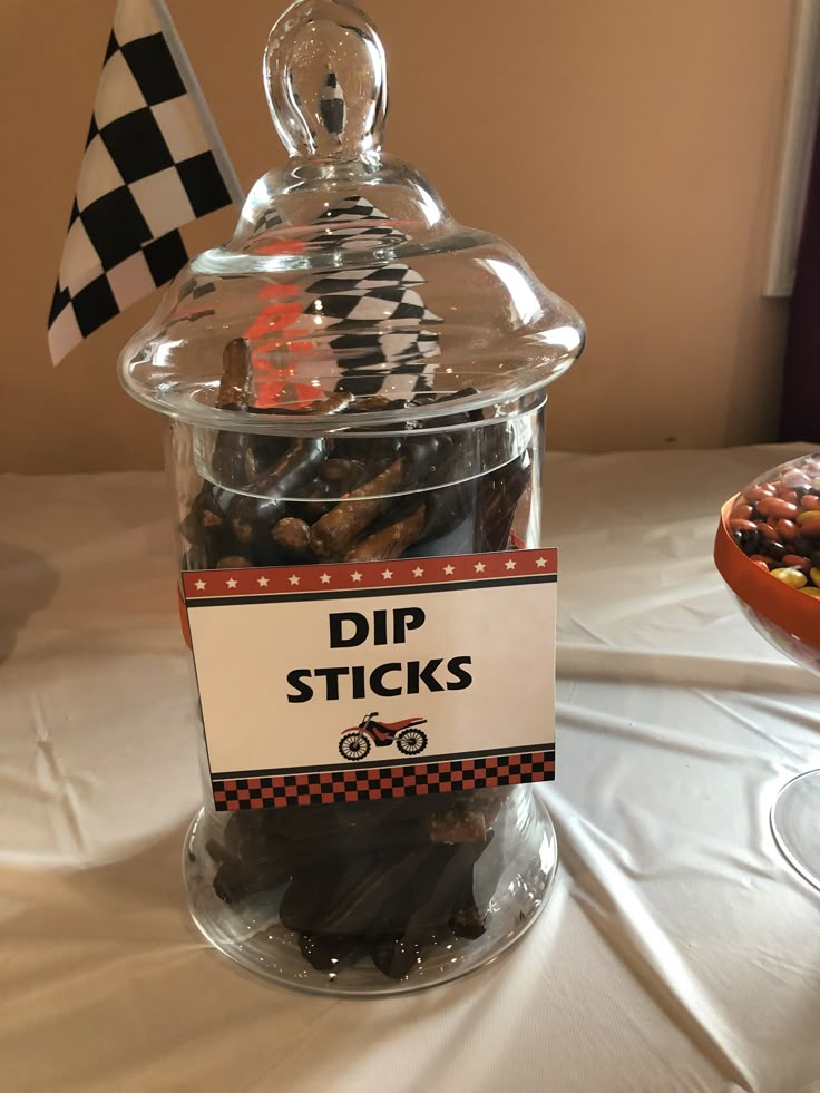 a glass jar filled with different types of candies on top of a white table cloth