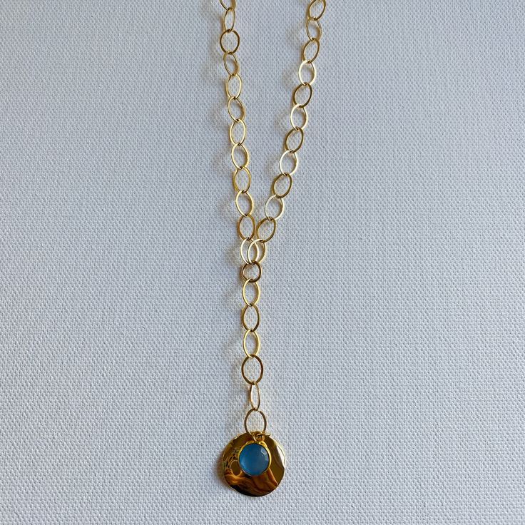 A blue sodalite gem is layered over a gold pendant and dangles from 2 inch lariat gold filled chain. The necklaces measures 18 inches and has a 3 inch lariat. Blue Jewelry With Detachable Pendant, Blue Jewelry With Detachable Round Pendant, Blue Lariat Jewelry With Adjustable Chain, Blue Lariat Necklace With Adjustable Chain, Blue Long Lariat Necklace With Adjustable Chain, Bohemian Blue 14k Gold-filled Jewelry, Blue Bohemian 14k Gold Filled Jewelry, Bohemian Blue 14k Gold Filled Jewelry, Blue Gemstone Lariat Necklace