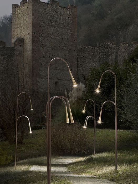 some lights that are on in the grass near a building with a castle behind it