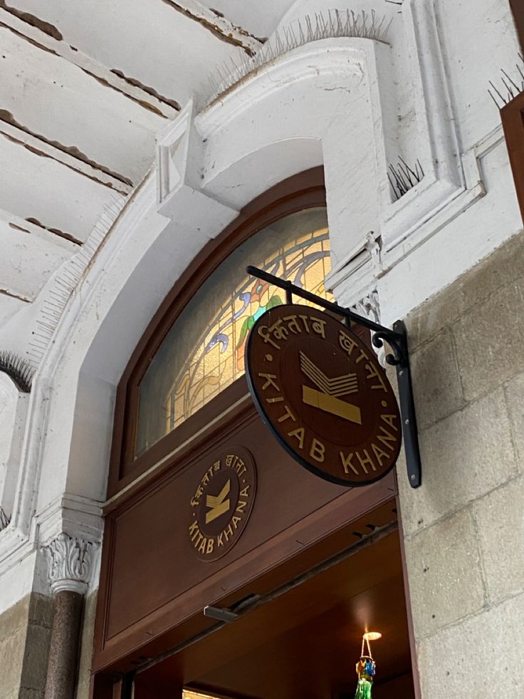 a sign hanging from the side of a building next to a doorway with a clock on it