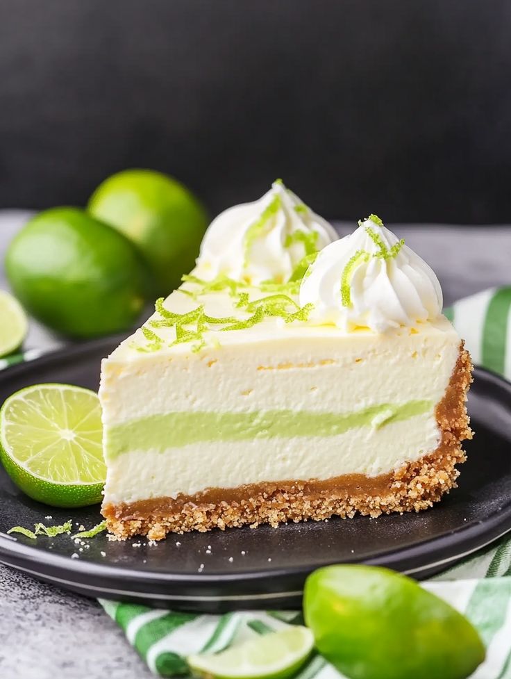 a slice of key lime cheesecake on a black plate with limes around it