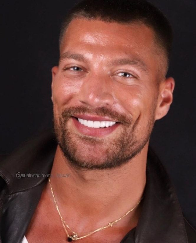 a close up of a person wearing a leather jacket and smiling at the camera with a smile on his face