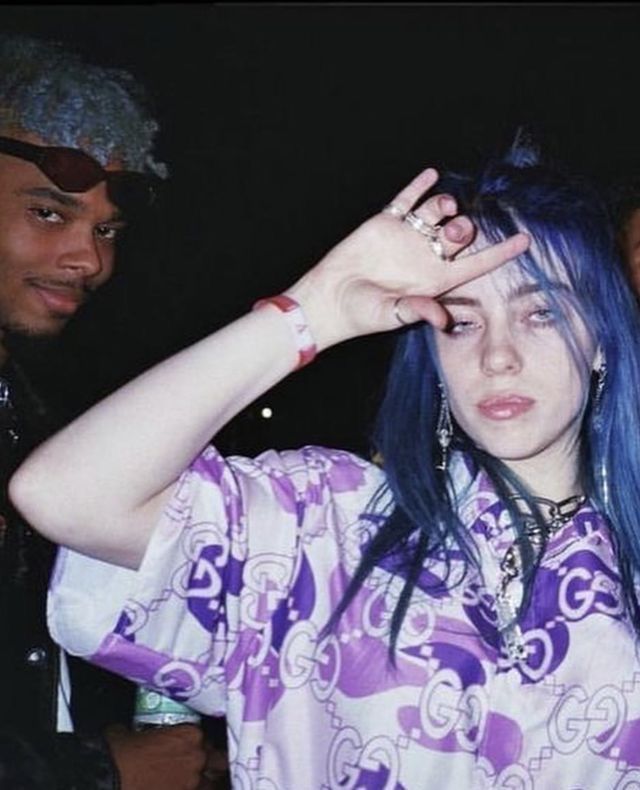 a woman with blue hair and piercings standing next to two men