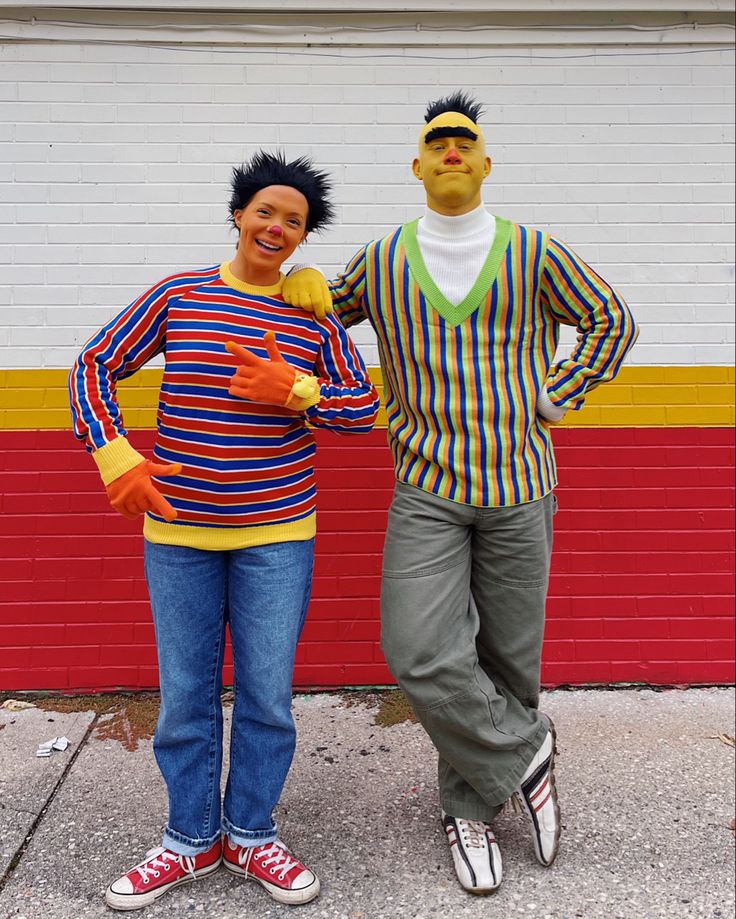 two people standing next to each other in front of a red and yellow wall,