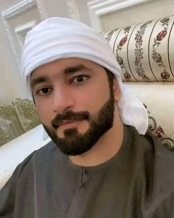 a man with a beard wearing a white turban sitting in front of a couch