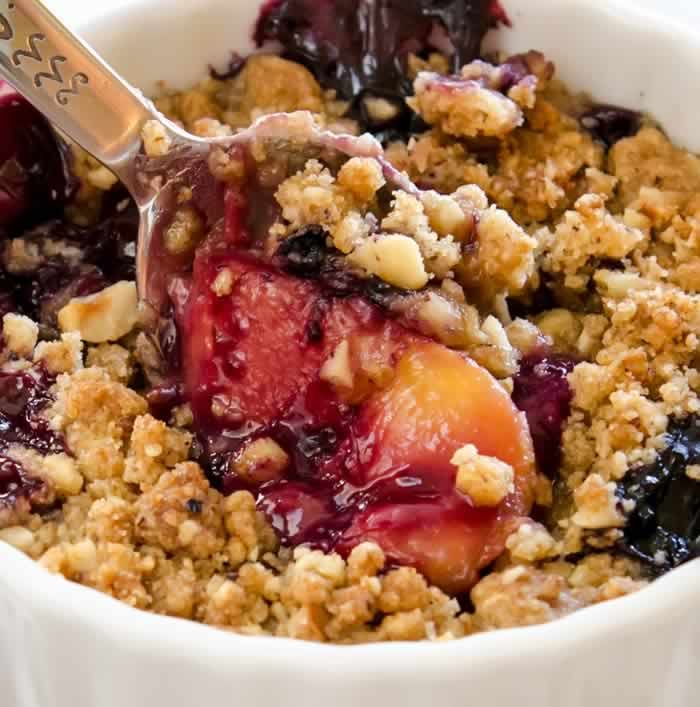 a close up of a bowl of food with fruit and crumbled toppings